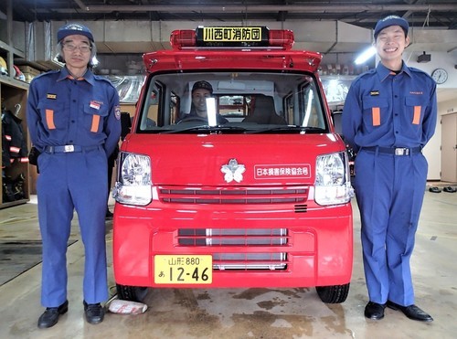 新しい車両の横に立つ消防団員